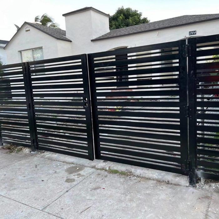 Black horizontal-slat aluminum gate fronting a South Florida home.