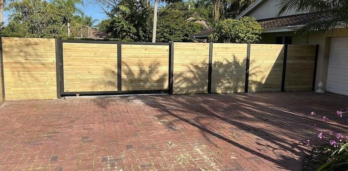 Wood horizontal-plank fence install on a brick paver driveway.