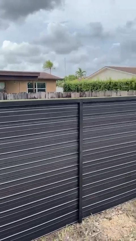Long run of dark Durafence slat panels in a South Florida neighborhood (powder-coated steel).