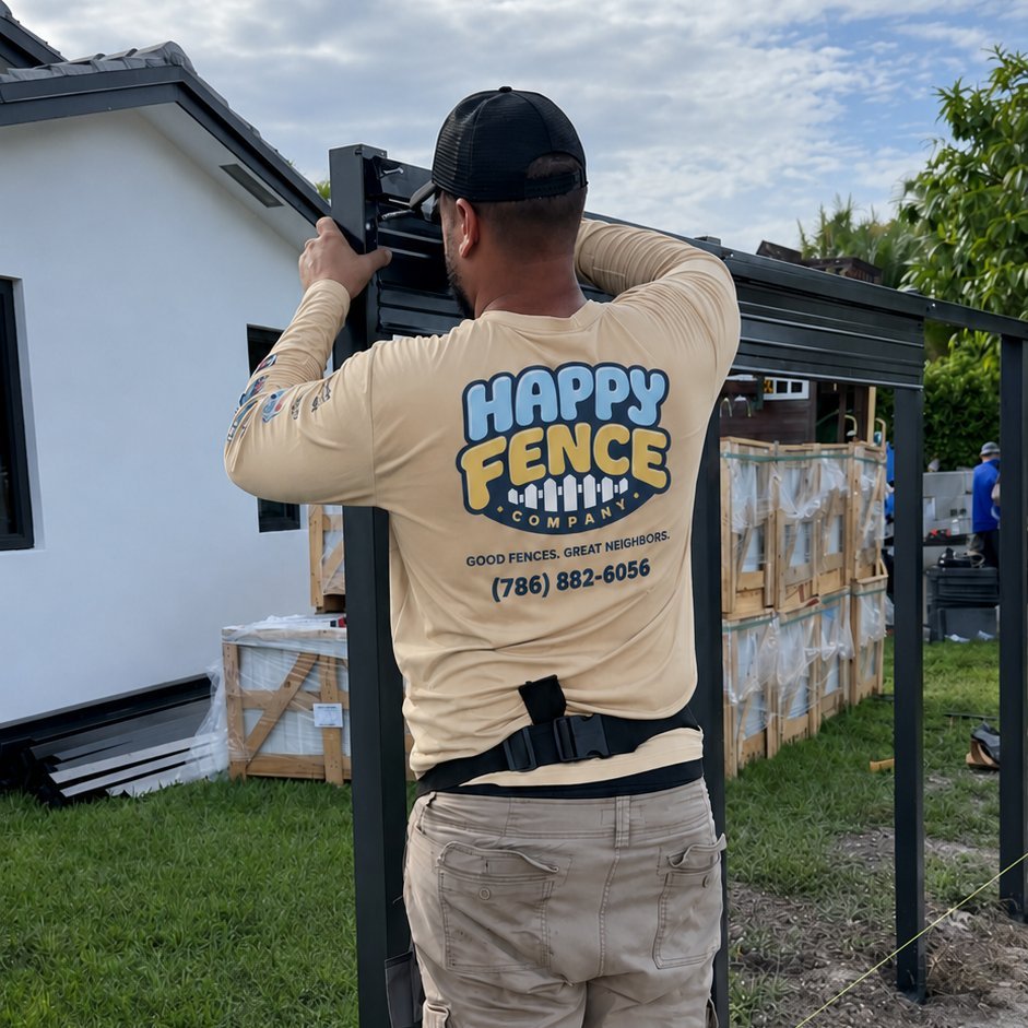 Happy Fence crew member from behind in branded long-sleeve, mid-install on a black powder-coated Durafence panel in a South Florida residential yard.
