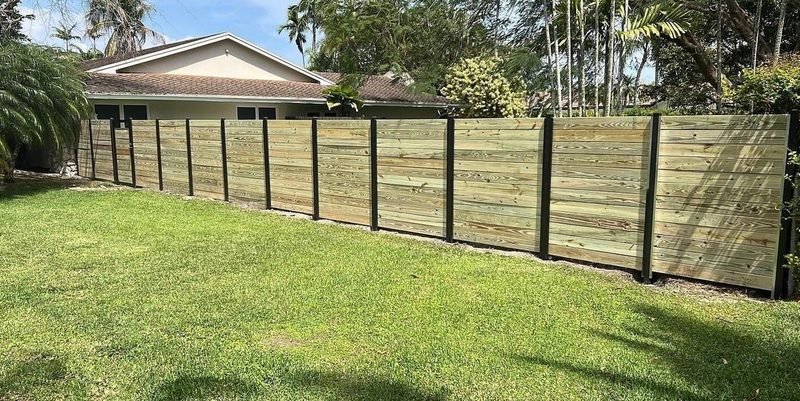 Wood horizontal-plank fence install in South Florida, framed by palm trees.